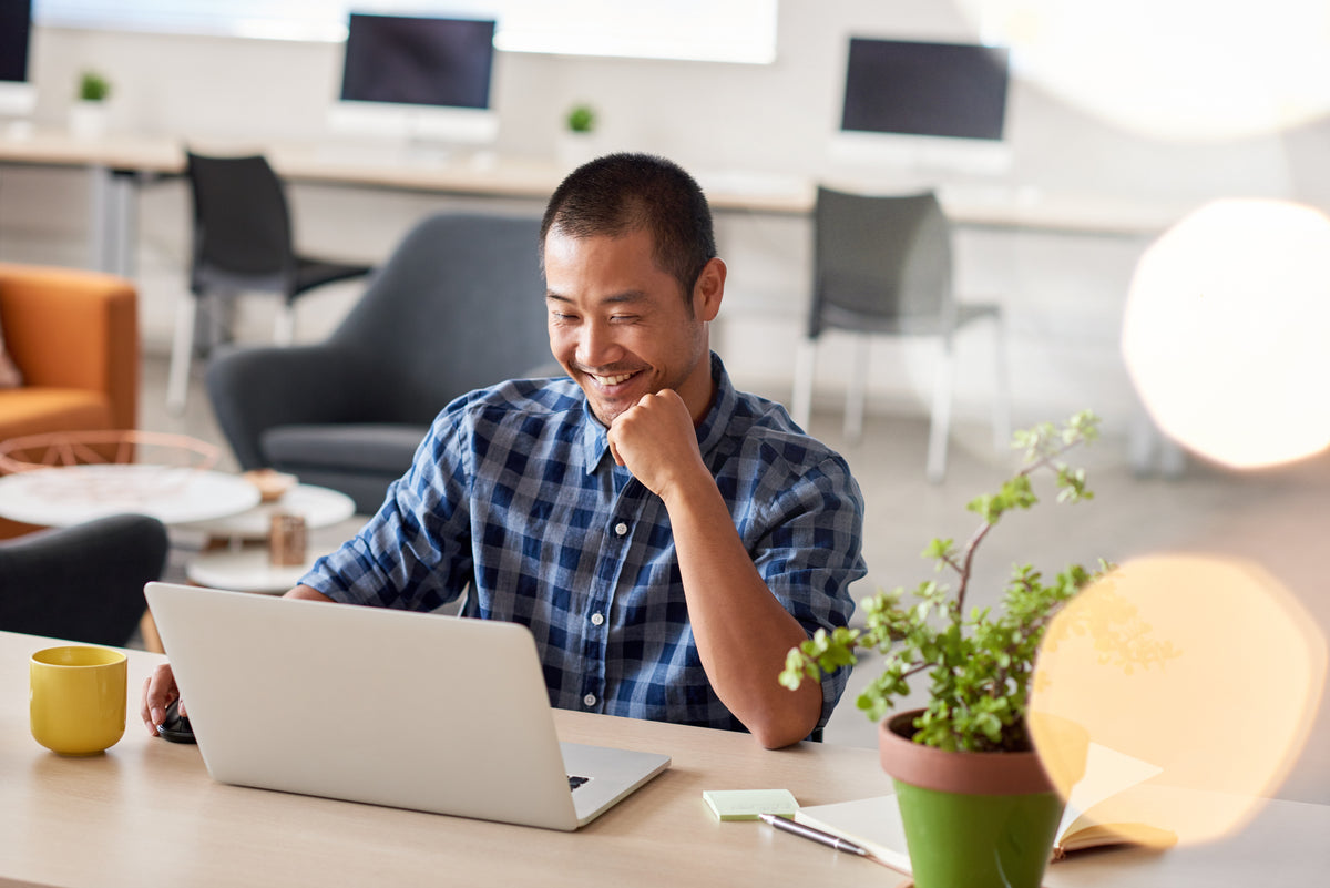 Man using a laptop at a desk in a modern office setting